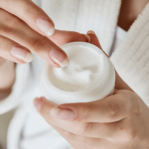 Frau hält Creme in der Hand und benutzt sie
