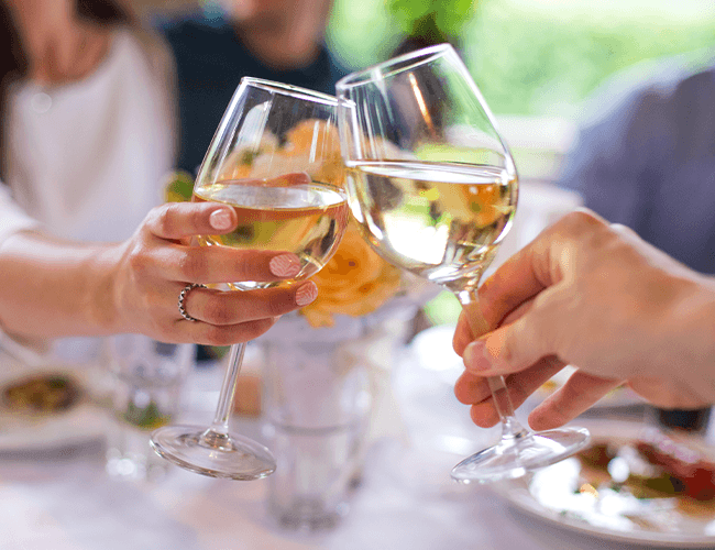 2 Weingläser die mit Weißwein anstoßen
