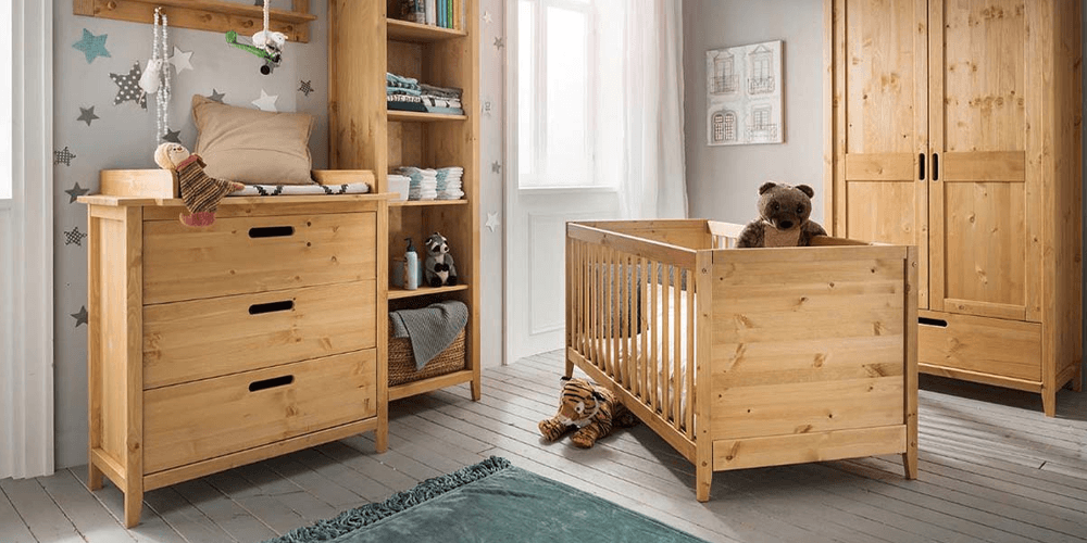 Kinderzimmer mit Babybett aus Holz und einem weißen Kleiderschrank