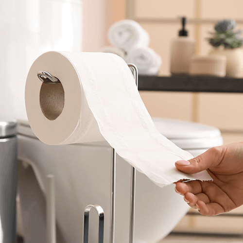 Nahaufnahme einer Hand, die Toilettenpapier abrollt