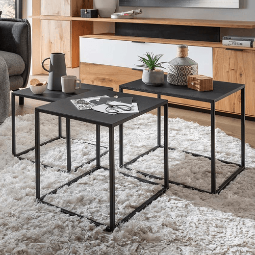 3 schwarze Couchtische auf einem beigen Teppich in einem Wohnzimmer